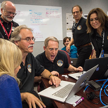 NASA Flikr: New Horizons Principal Investigator Alan Stern of Southwest Research Institute (SwRI), center, along with other team members, reacts as he views new images from the spacecraft for the first time, Wednesday, July 15, 2015 at Johns Hopkins University Applied Physics Laboratory (APL) in Laurel, Md.