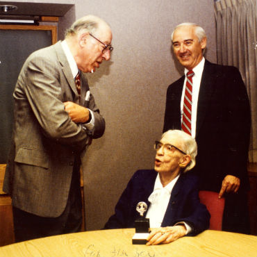 Jim Dean, in 1989, is pictured standing behind RADM Grace Hopper during a discussion with Fred Friendly. Photograph courtesy of Jim Dean. 