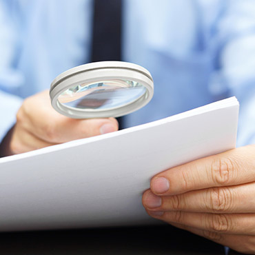 Shutterstock image (by Bacho): Businessman looking through a magnifying glass at a contract.